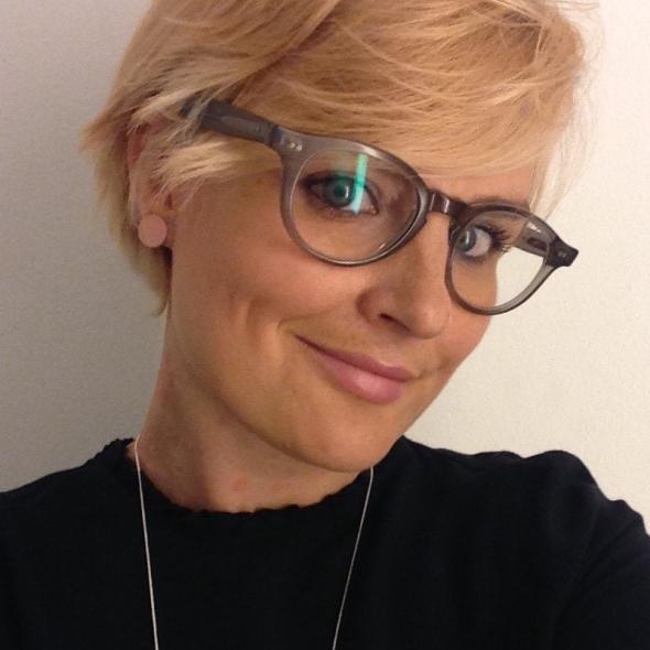 Headshot of person with short blonde hair and dark rimmed glasses 