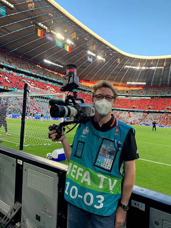 Flynn Hamilton holding a camera at the side of a football pitch