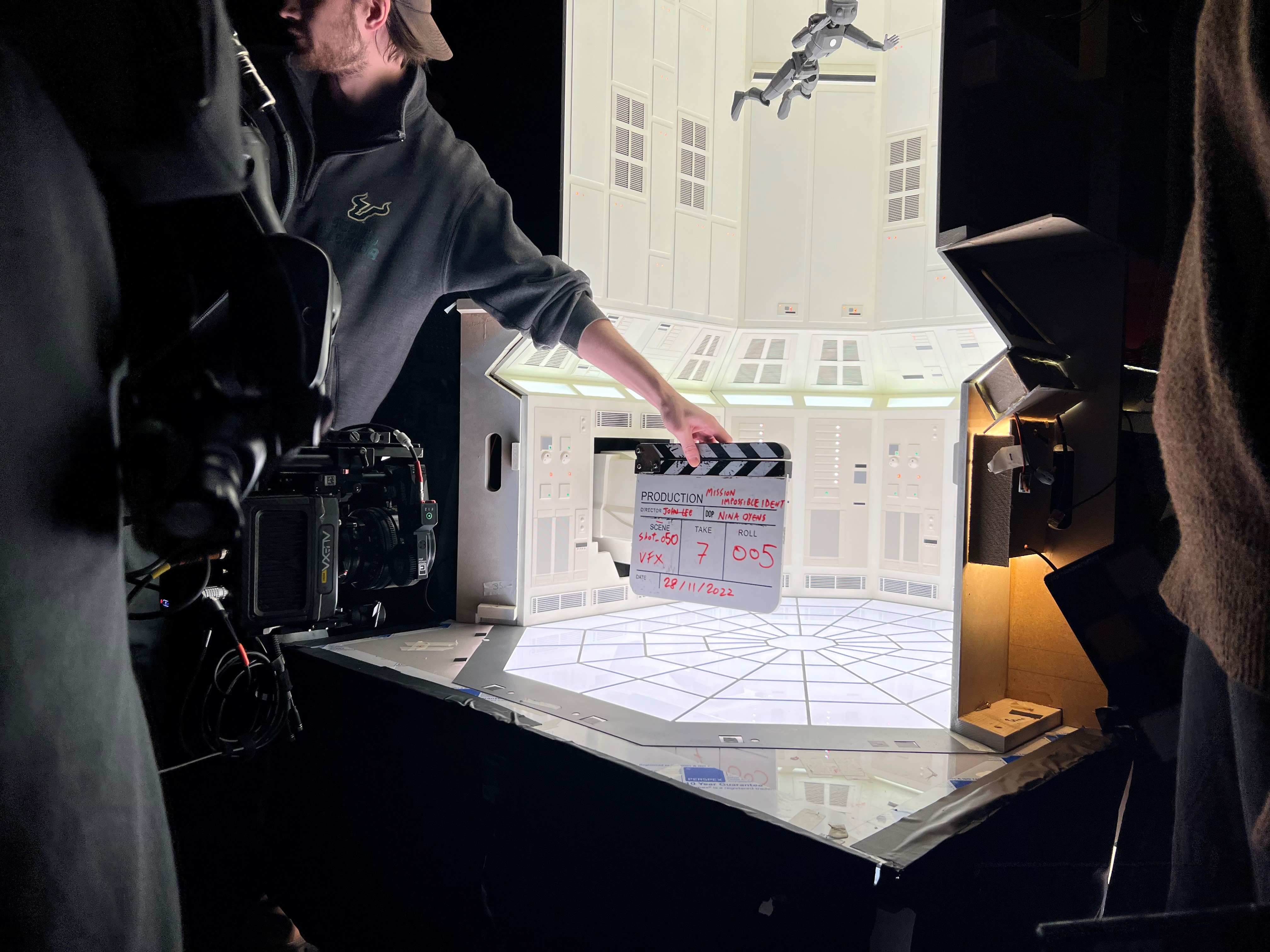 person holding clapperboard in front of model