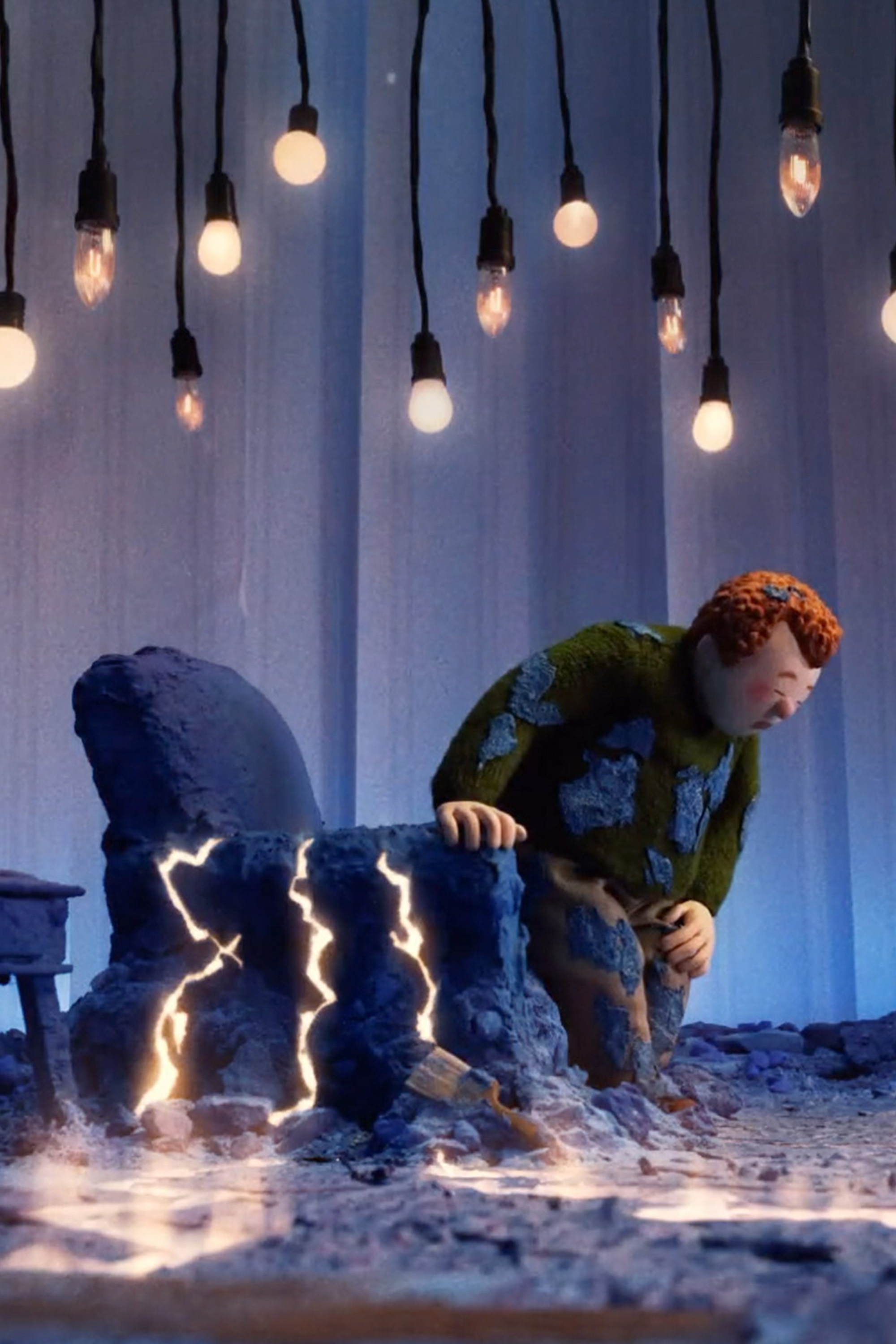 B&Q advert - man leaning on sofa chair surrounded by lights and electricity