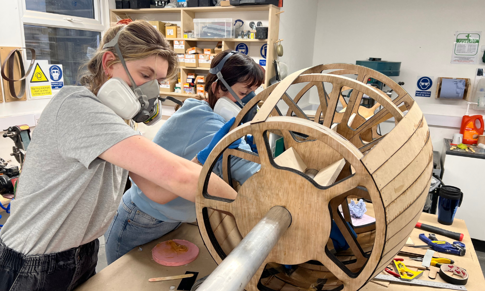 Two women working on wooden model