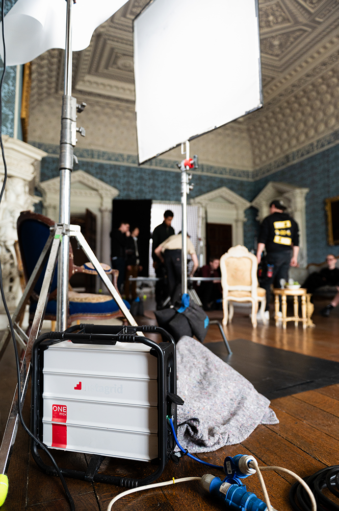 instagrid battery in foreground of students filming in stately room