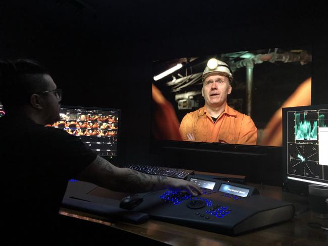 student at colour grading desk with image of coal miner on screen
