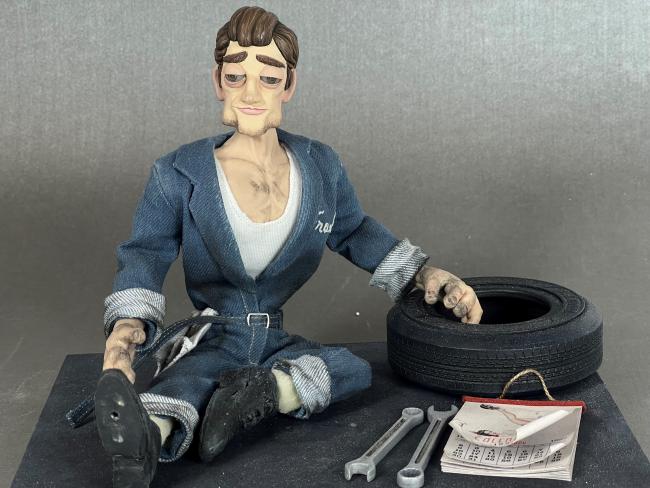 model of a mechanic sat next to a tire and some tools