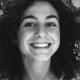 Black and white image of the head of a woman with curly hair smiling 