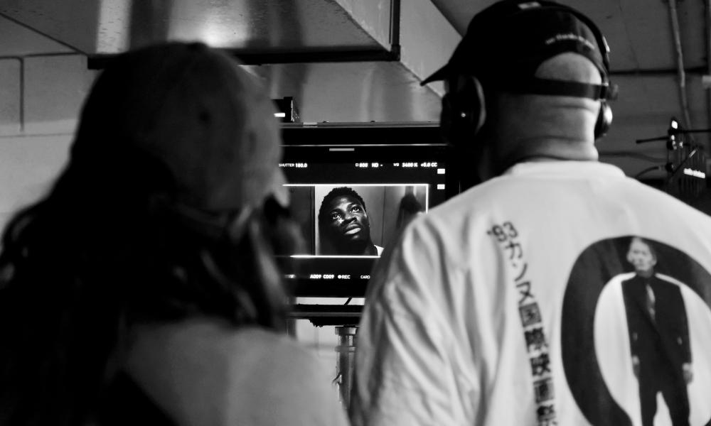 two people stood with back to camera looking at camera monitor