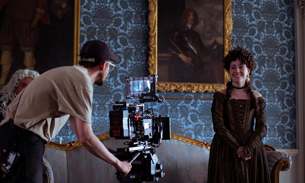 man filming woman in period costume