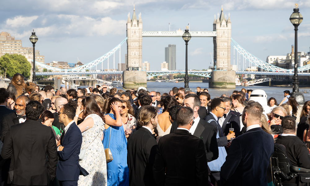 Sun setting on crowd gathered outside old billingsgate with the Thames and Tower Bridge in the background