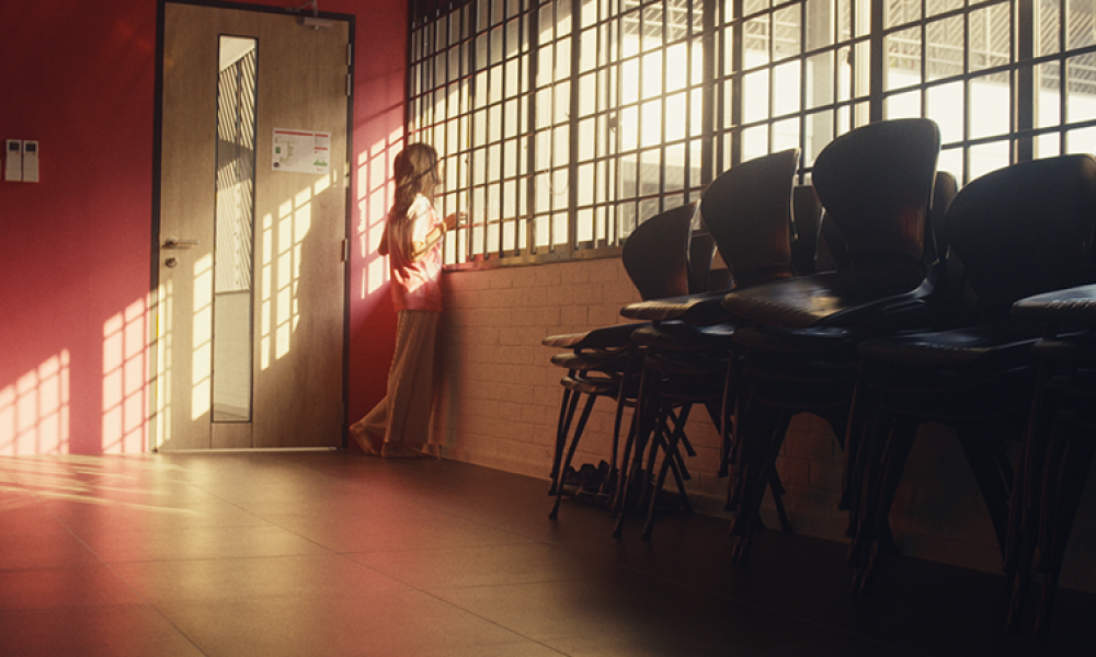 Still from film of woman looking out barred windows