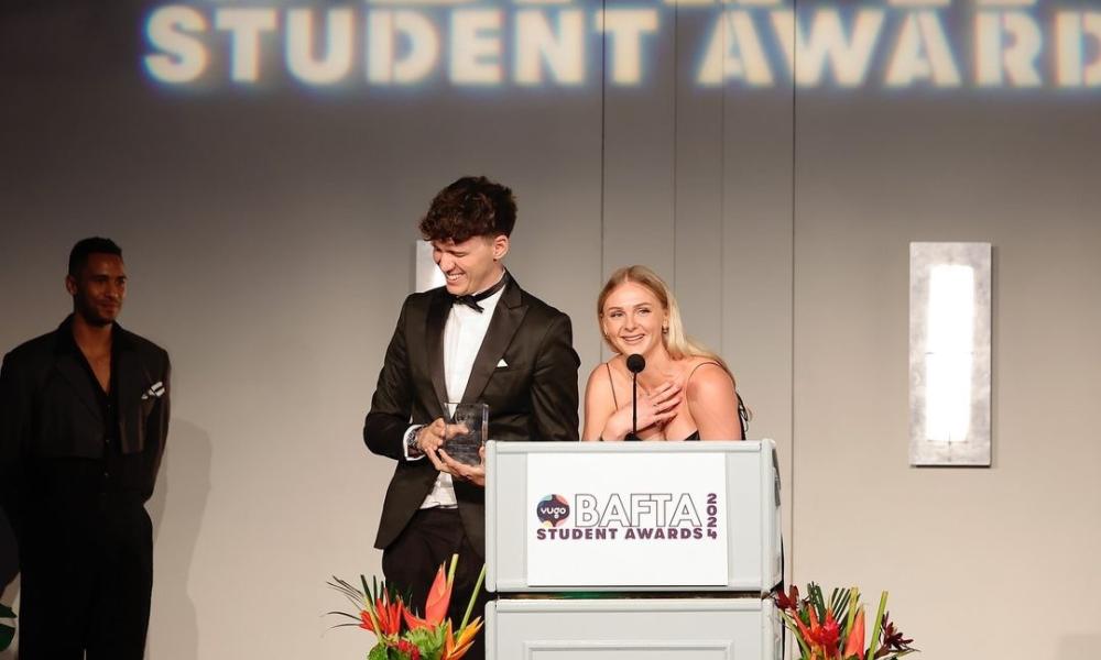 Two people on stage accepting award