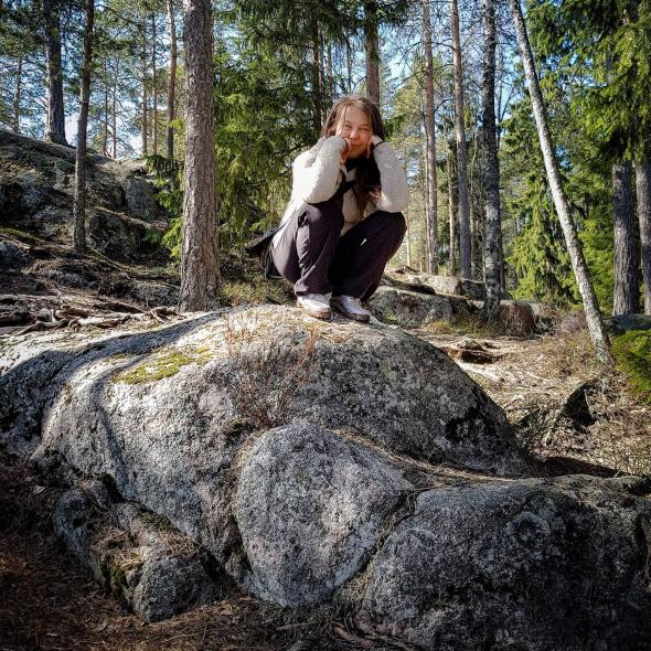 Woman crouched on a rock in a woodland