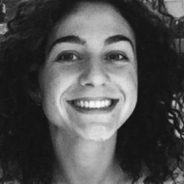 Black and white image of the head of a woman with curly hair smiling 