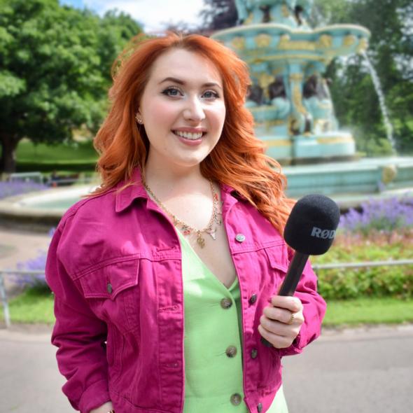 Photo of Alice with a microphone in front of a fountain