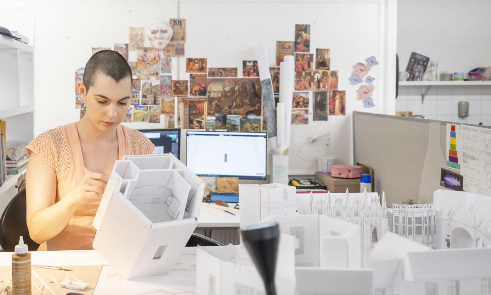 Model making student building small-scale ancient city set for film