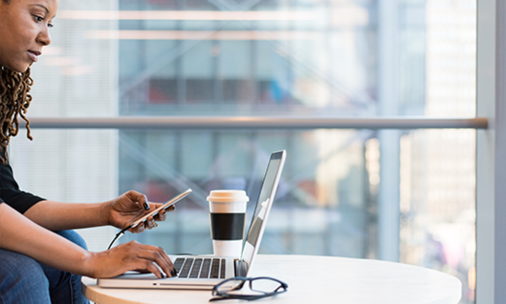 woman at table with laptop, phone and coffee